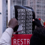 A protester puts a George Floyd poster on security fencing at the Hennepin County Government Center, where the Derek Chauvin murder trial is being held.