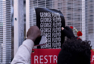 A protester puts a George Floyd poster on security fencing at the Hennepin County Government Center, where the Derek Chauvin murder trial is being held.