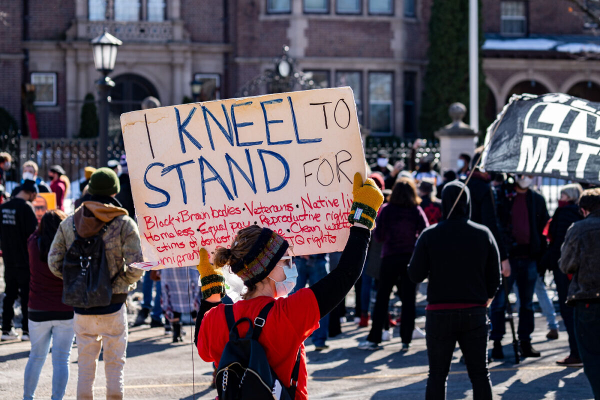 A protester holds up a sign at a rally outside the Minnesota Governor's Residence.