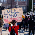 A protester holds up a sign at a rally outside the Minnesota Governor's Residence.