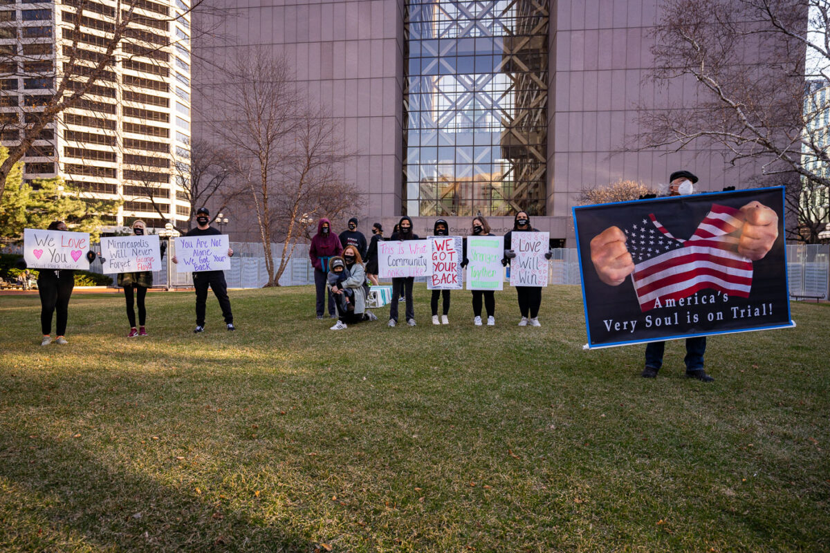 Protesters hold up signs outside the Hennepin County Government Center as opening statements in the Derek Chauvin murder trial begin.