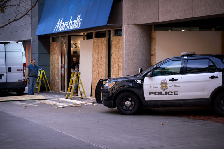 Minneapolis Marshalls Boarded Up for Chauvin Trial Security 1 In anticipation of the Derek Chauvin murder trial, storefronts in downtown Minneapolis were boarded up as a security measure. The image shows workers installing plywood over the windows of a Marshalls store, with a Minneapolis Police Department vehicle parked nearby. This preparation reflected concerns about potential unrest and property damage, echoing events that followed the murder of George Floyd in the same city in 2020.