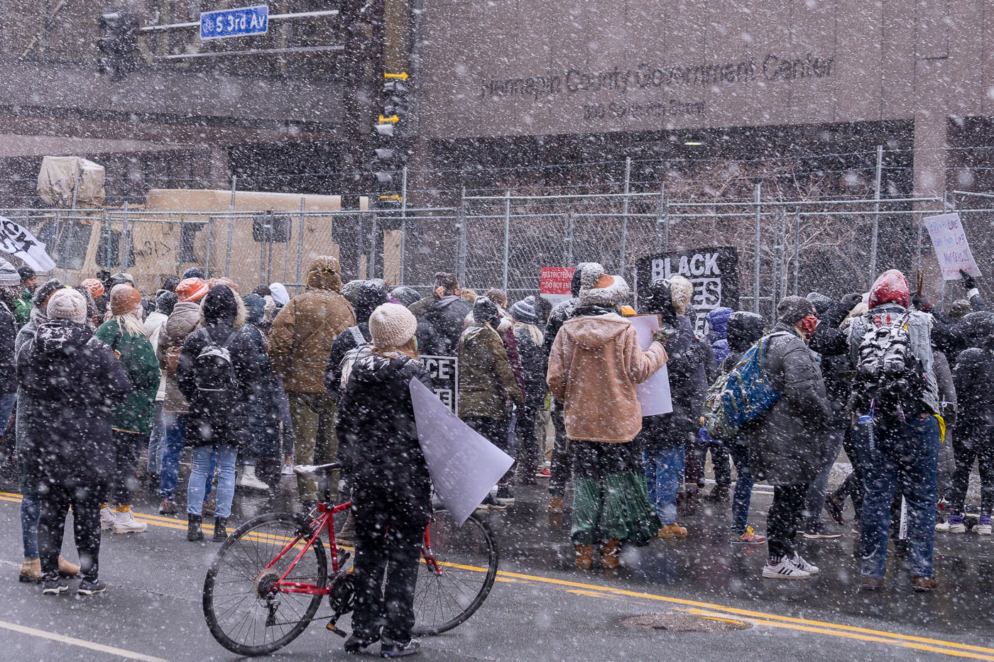 Snow falls at Hennepin County Courthouse with protesters