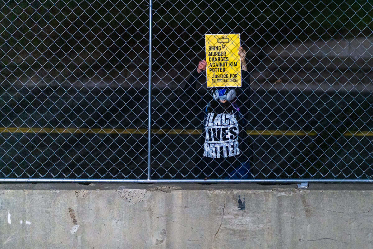 A protester holds up a sign outside the Hennepin County Government Center asking for murder charges against Kim Potter.