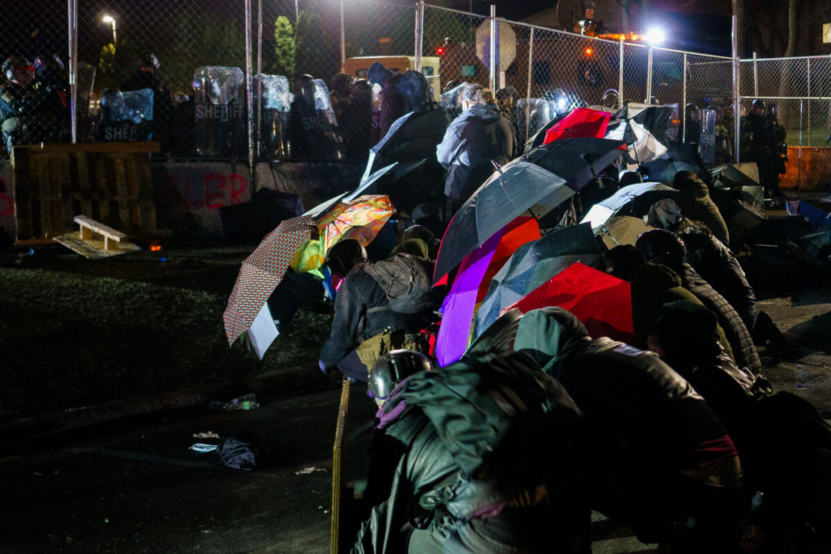 Protesters with umbrellas outside the Brooklyn Center Police Department.