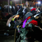 Protesters with umbrellas outside the Brooklyn Center Police Department.