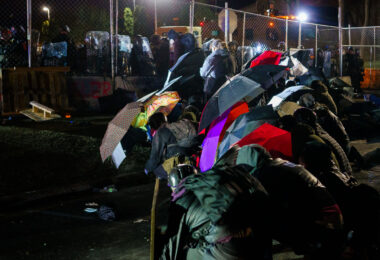 Protesters with umbrellas outside the Brooklyn Center Police Department.