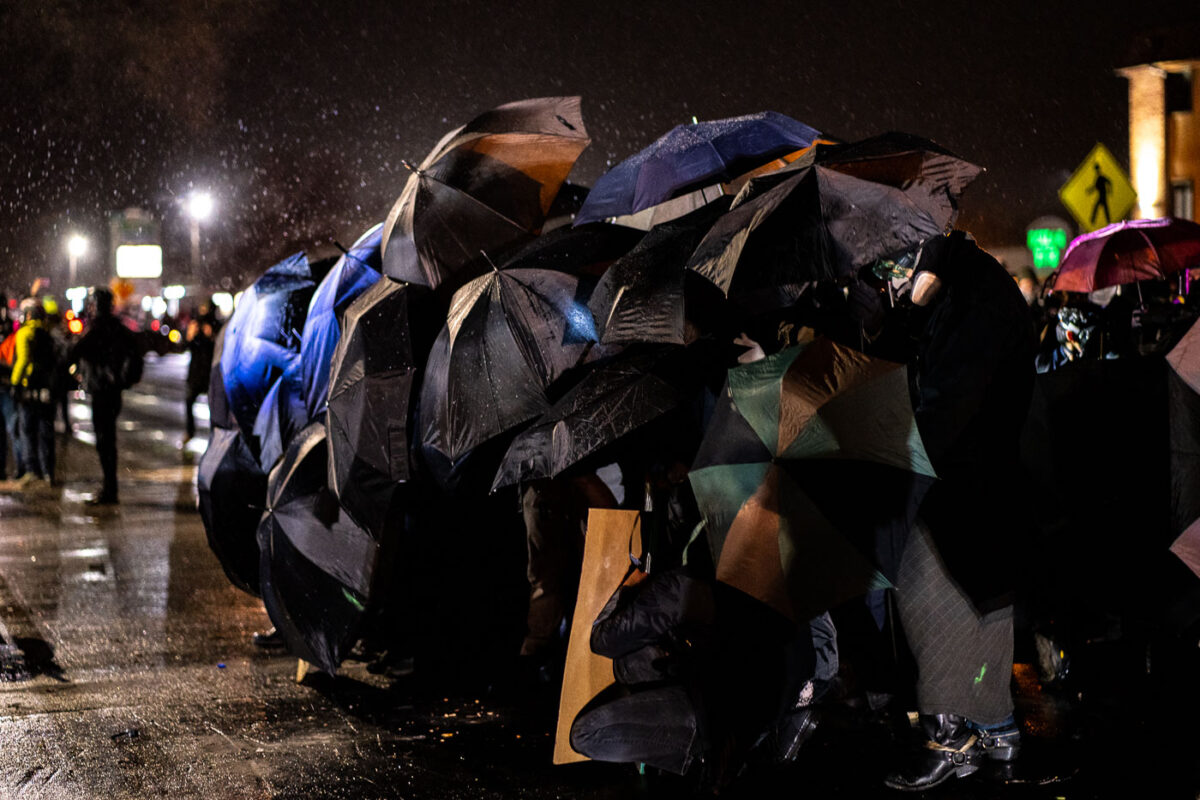 Protesters use umbrellas to shield themselves from chemical irritants being used by police outside the Brooklyn Center Police Department. Protesters are protesting the shooting death of 20-year old Daunte Wright on April 11th, 2021.