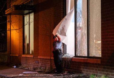 A Minneapolis Police Officer holds open a window for those inside a looted Walgreens to leave on April 11, 2021. Earlier in the day Daunte Wright was killed by Brooklyn Center police officer Kim Potter.