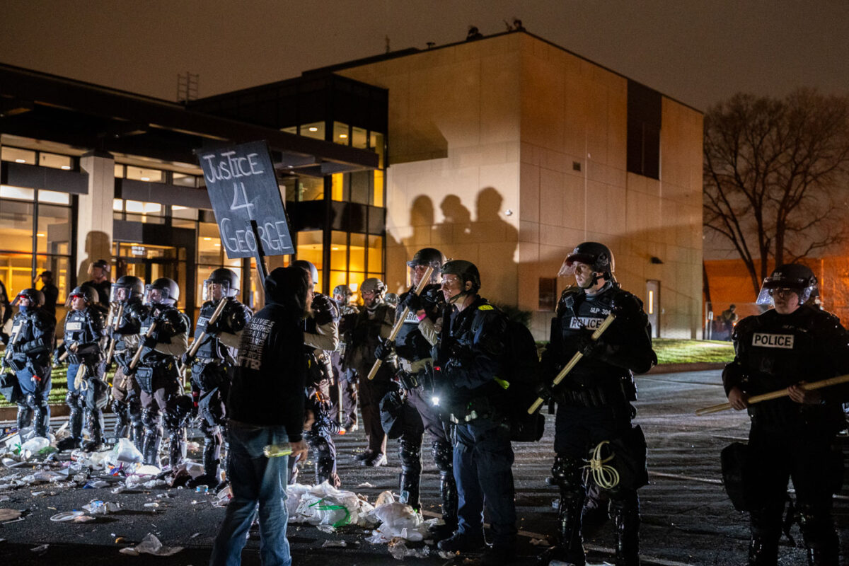 A protester holding a "Justice 4 George" sign yells at police outside the Brooklyn Center Police Department.