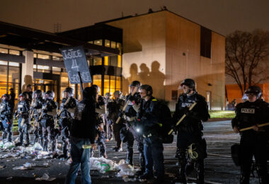 A protester holding a "Justice 4 George" sign yells at police outside the Brooklyn Center Police Department.