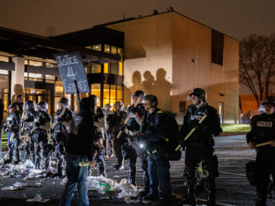 Protester with Justice 4 George sign faces police at Brooklyn Center PD