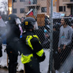 Protesters and police officers with fencing in between them.
