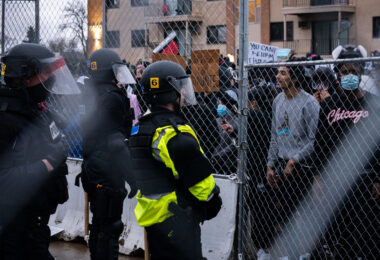 Protesters and police officers with fencing in between them.