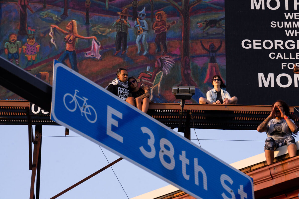 The community sits on rooftop billboards watching Common perform with The Sound of Blackness at George Floyd Square on the 1 year anniversary of the murder of George Floyd. 

George Floyd Square has been community controlled since May 26th, 2020.