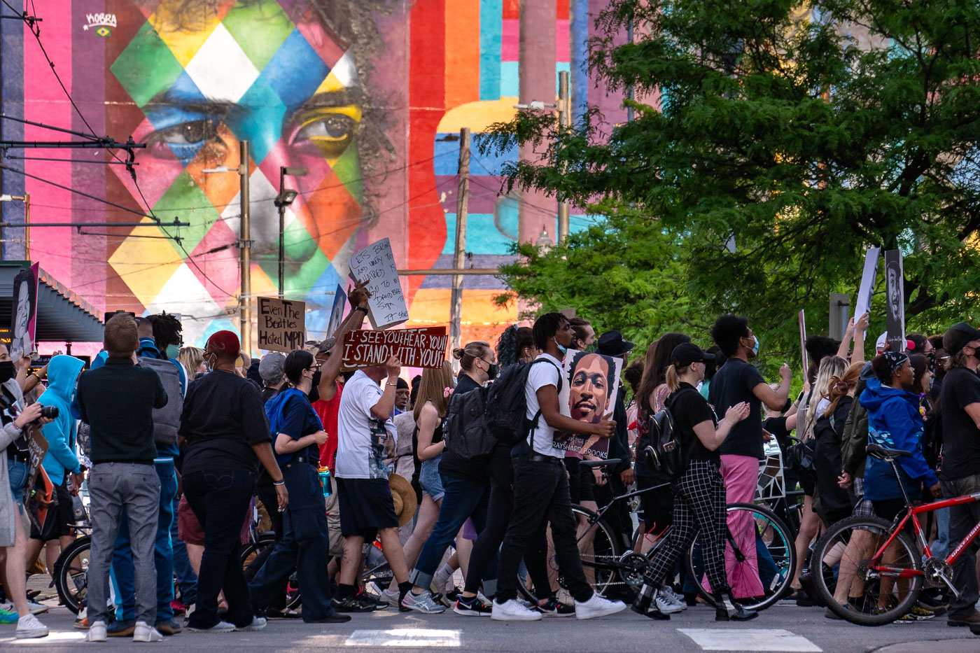 Protesters walk past Bob Dylan mural by Kobra in Minneapolis