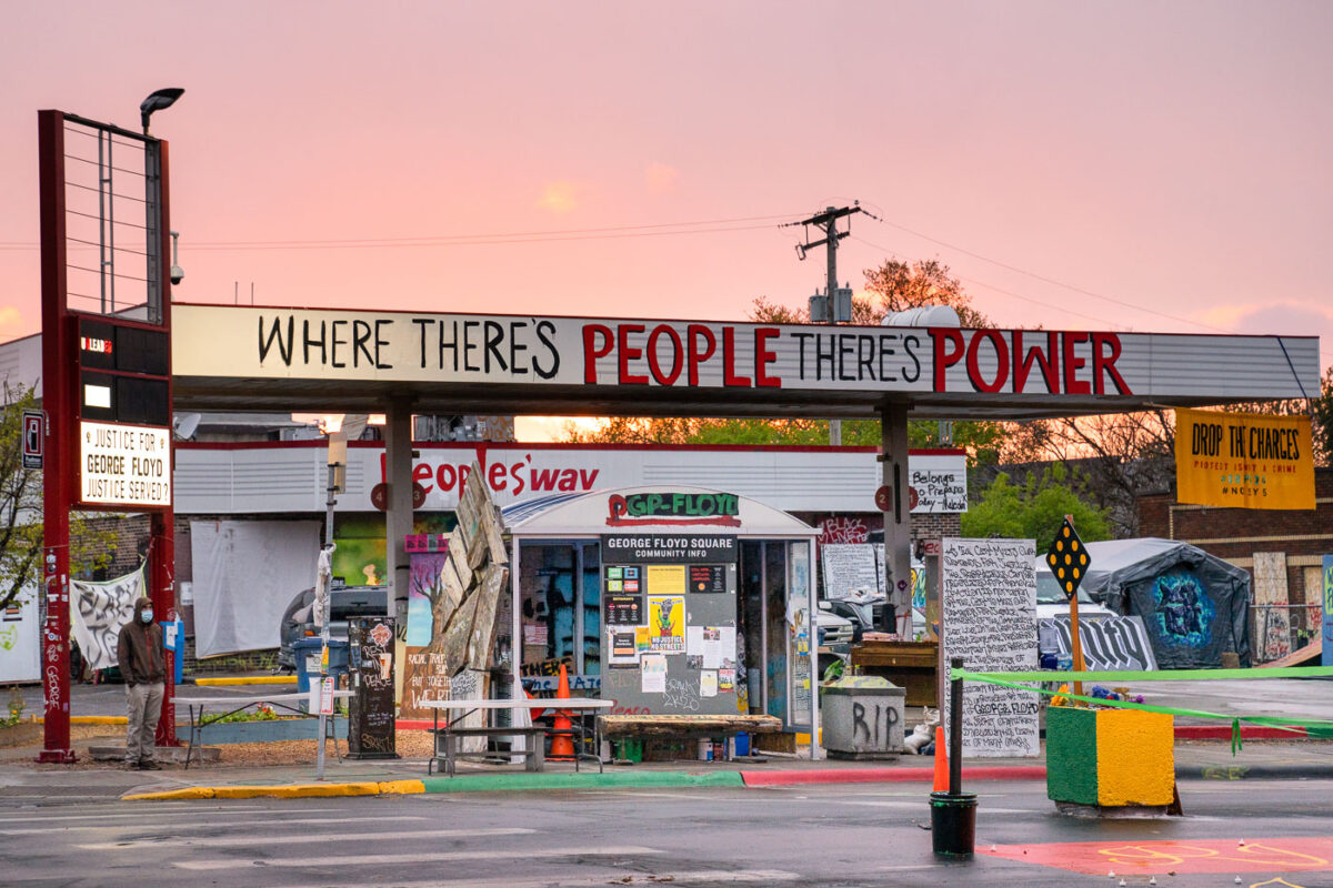 The sun sets behind The Peoples Way at George Floyd Square.