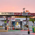 The sun sets behind The Peoples Way at George Floyd Square.