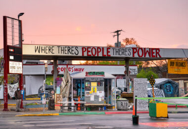 The sun sets behind The Peoples Way at George Floyd Square.