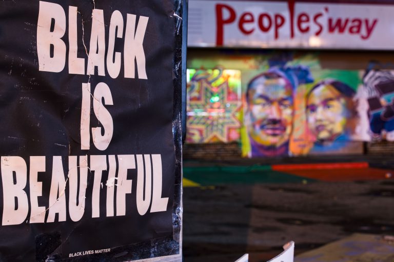 "Black Is Beautiful" Poster Near The People's Way at George Floyd Square 1 A "Black Is Beautiful" sign at George Floyd Square in Minneapolis, with colorful mural and "People's Way" signage visible behind.