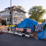 Black Lives Matter sign hung over blue tarps over barricades at 38th Street and Elliott at George Floyd Square. City workers removed barricades the day before.