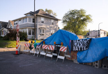 Black Lives Matter sign hung over blue tarps over barricades at 38th Street and Elliott at George Floyd Square. City workers removed barricades the day before.