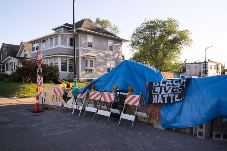 Black Lives Matter on George Floyd Square barricades 1 Black Lives Matter sign hung over blue tarps over barricades at 38th Street and Elliott at George Floyd Square. City workers removed barricades the day before.