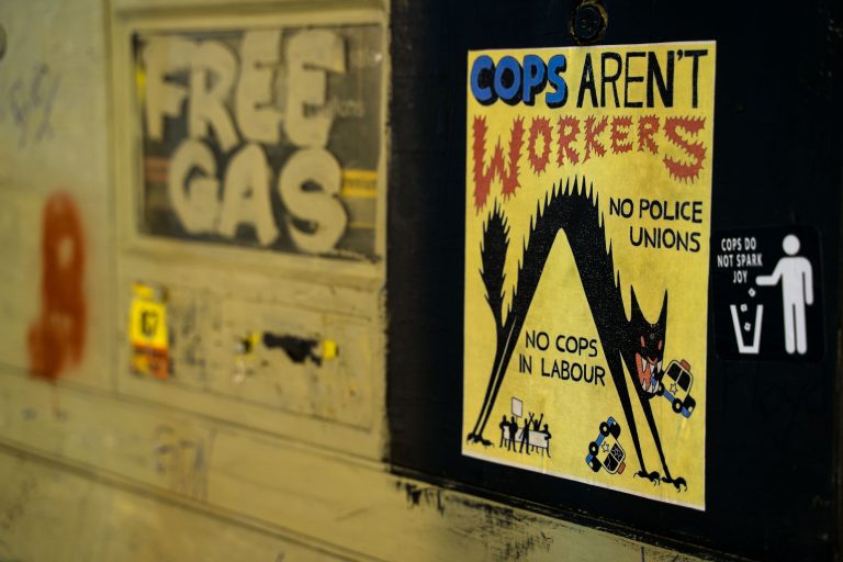 "Cops Aren't Workers" Poster on a Gas Pump at George Floyd Square 1 A yellow protest poster reading "Cops Aren't Workers" with anti-police messaging attached to a gas pump in George Floyd Square, Minneapolis.