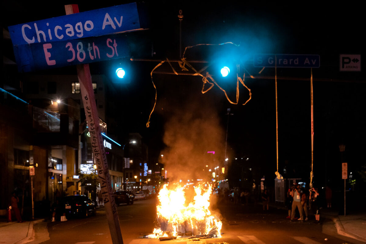 Protesters burn garbage cans in the evening after Winston Smith was killed by law enforcement in the nearby parking garage.