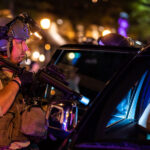 Hennepin County Sheriff officer points his weapon at someone inside a vehicle near Winston Smith protests. Smith was killed by law enforcement days earlier.