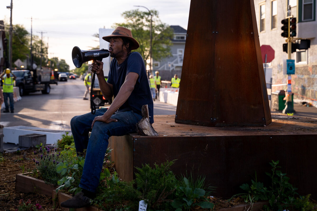 Jay Webb speaks at the garden in George Floyd Square while the city is opening the square to vehicle traffic.