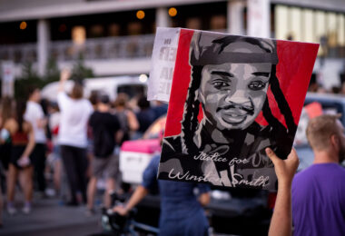 Protester holds up a Justice for Winston Smith sign on Lake Street during protests following the shooting death of Winston Smith on June 3rd by a Federal Task Force.

The day prior Deona Marie was killed when Nicholas Kraus drove his vehicle into those protesting the killing of Smith.