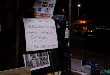 A sign at George Floyd Square reading "Please take what u need, don't be greedy or stealing. Everything is for everybody. Take care of each other"