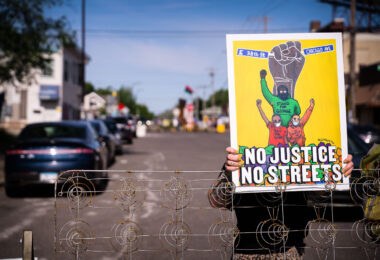 A woman holds a "No Justice No Streets" yard sign on the day the city tried to clear out barricades around the square.