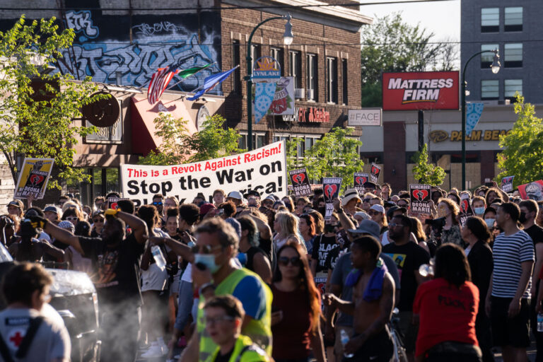 This is a revolt against racism protest sign 1 Protesters carrying signs that read "This is a Revolt Against Racism! Stop the War on Black America!" while marching through the streets of Uptown Minneapolis.Protesters have been marching since the June 3rd law enforcement shooting death of Winston Smith and the June 13th killing of protester Deona Marie. Marie was killed when Nicholas Kraus drove his vehicle into those protesting the killing of Smith.
