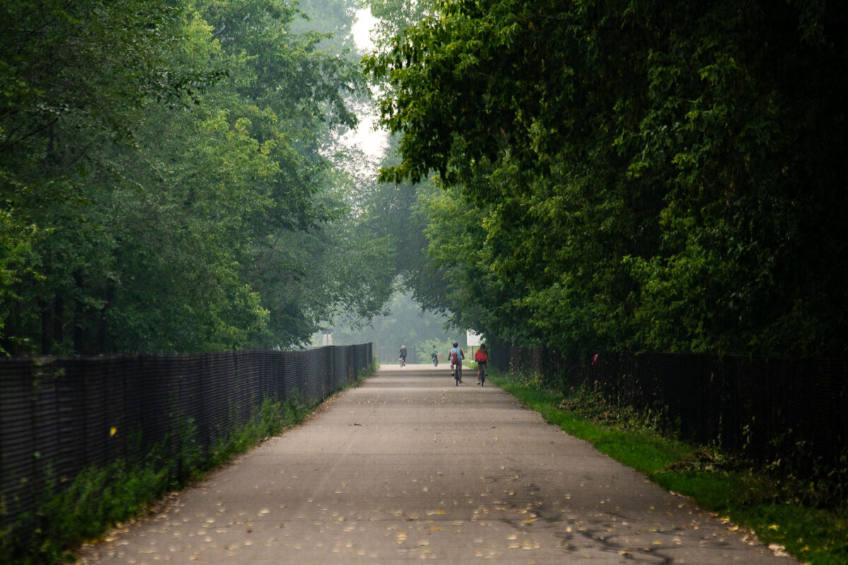 Bikers biking down the Midtown Greenway while wildfire smoke from Canada blankets Minneapolis.