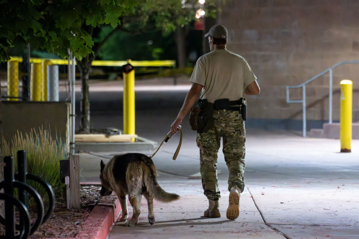A private security guard walks the grounds of a parking ramp with a dog.