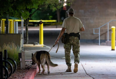 A private security guard walks the grounds of a parking ramp with a dog.