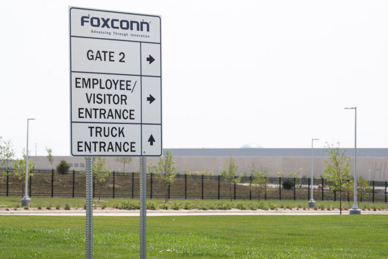 Foxconn Campus Entrance, Mount Pleasant, Wisconsin 1 A directional sign marks Gate 2 at Foxconn’s Mount Pleasant campus in Racine County, Wisconsin. Erected as part of the large industrial complex originally envisioned for advanced LCD and electronics production, the site now houses scaled-down operations and support facilities. The distant dome visible behind the sign is part of the “Globe” building — a glass sphere that has become an unintended architectural landmark representing both the scale and shifting ambitions of the Foxconn development.