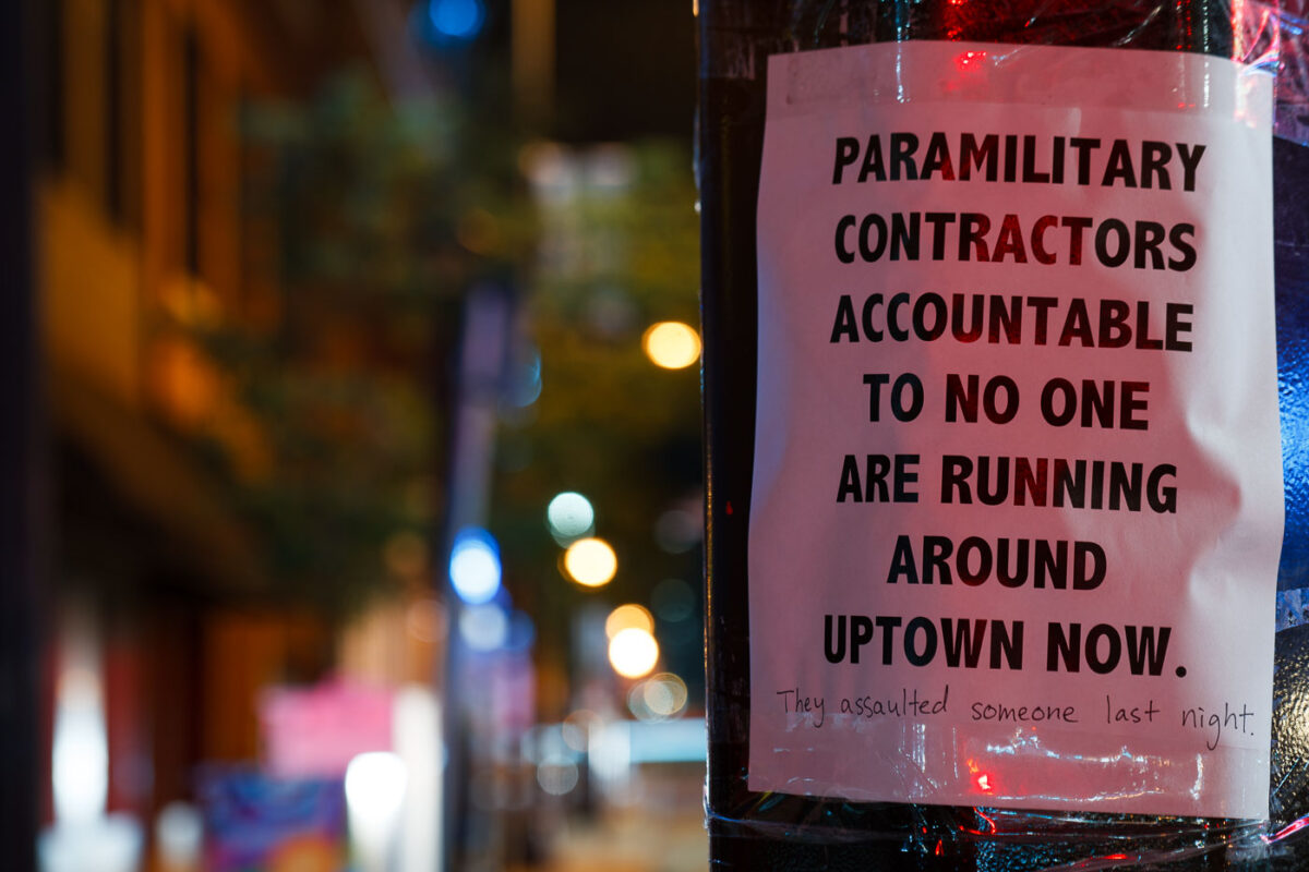 A sign reading "Paramilitary contractors accountable to no one are running around uptown now." with "They assaulted someone last night." added to the bottom. The sign was seen after a private security company cleared and started to patrol the Winston Smith and Deona Marie Memorial sites.