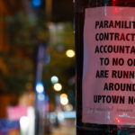 A sign reading "Paramilitary contractors accountable to no one are running around uptown now." with "They assaulted someone last night." added to the bottom. The sign was seen after a private security company cleared and started to patrol the Winston Smith and Deona Marie Memorial sites.