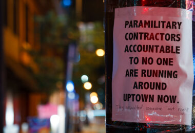 A sign reading "Paramilitary contractors accountable to no one are running around uptown now." with "They assaulted someone last night." added to the bottom. The sign was seen after a private security company cleared and started to patrol the Winston Smith and Deona Marie Memorial sites.