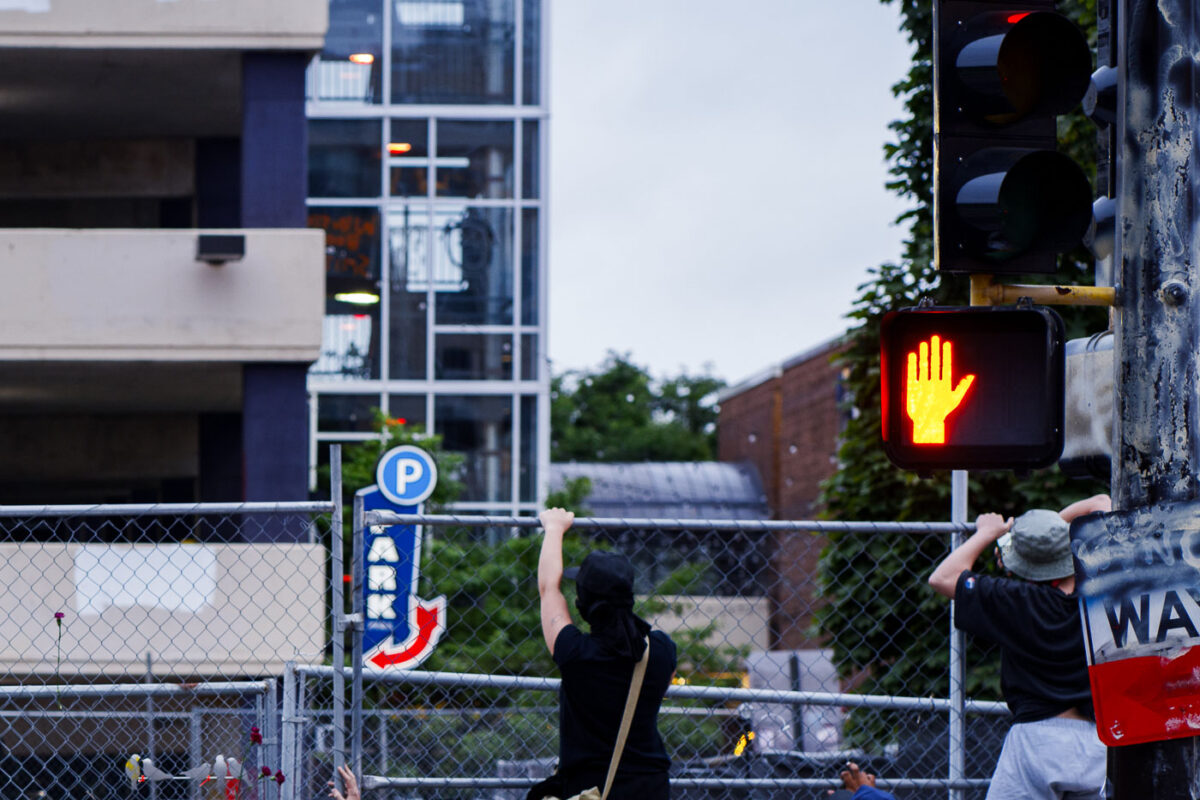 Protesters climb the fence outside the Winston Smith and Deona Marie memorials. The memorials had been cleared by private security contractors earlier in the morning.