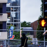 Protesters climb fencing at Winston Smith protest site 4 Protesters climb the fence outside the Winston Smith and Deona Marie memorials. The memorials had been cleared by private security contractors earlier in the morning.