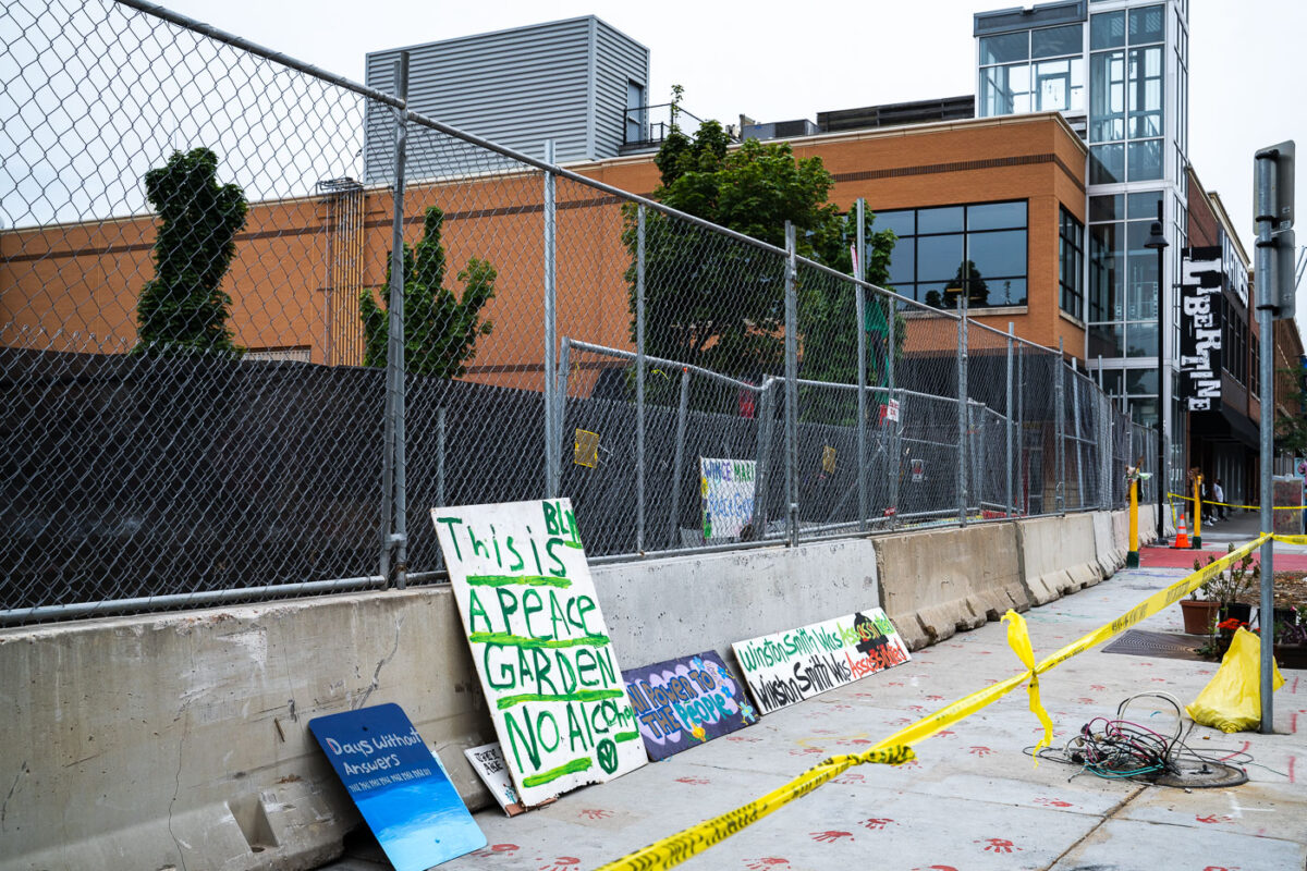 Signs laying against newly installed barricades outside what was the Winston Smith and Deona Marie Memorials.