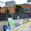 Signs laying against newly installed barricades outside what was the Winston Smith and Deona Marie Memorials.