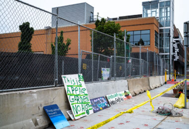 Signs laying against newly installed barricades outside what was the Winston Smith and Deona Marie Memorials.