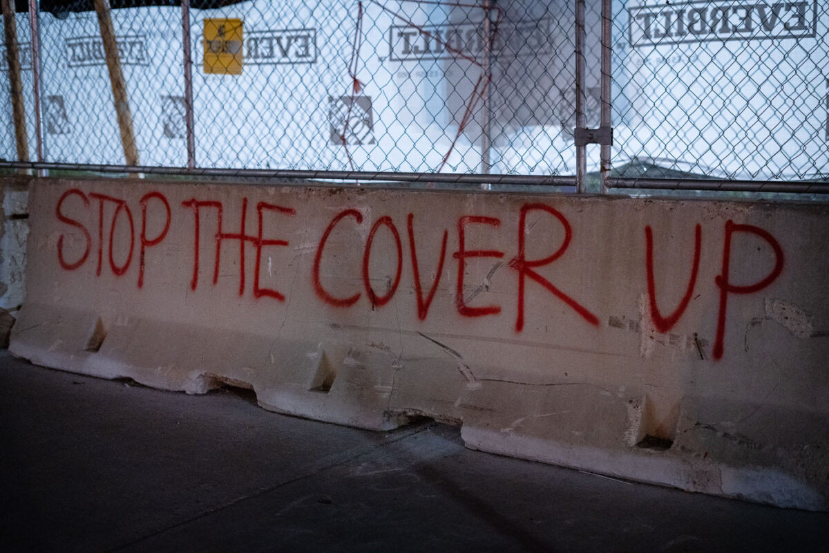 "Stop The Cover Up" painted on a concrete barrier outside the parking ramp where Winston Smith was killed by law enforcement.