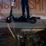 A protester rides a Scooter across barricades that read "Winston Smith" in Uptown Minneapolis on Lake Street.