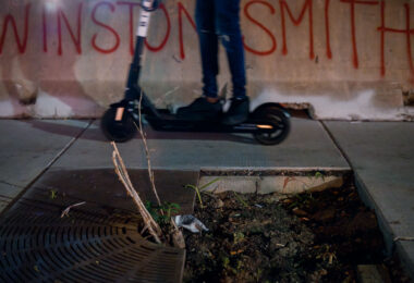 A protester rides a Scooter across barricades that read "Winston Smith" in Uptown Minneapolis on Lake Street.